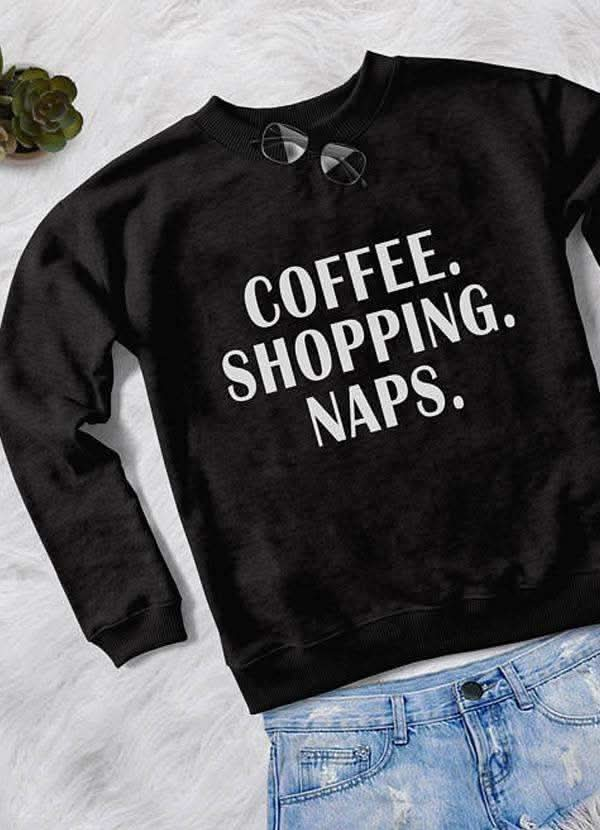  "Black sweatshirt with the text 'COFFEE. SHOPPING. NAPS.' displayed, laid out with light-colored jeans on a white background."