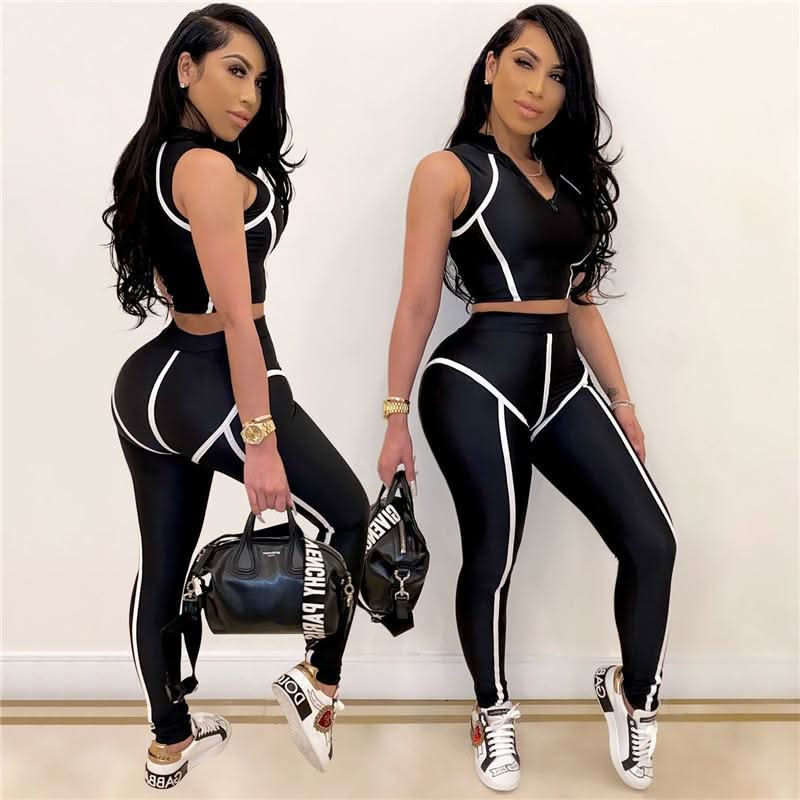 “Two women modeling matching black and white activewear sets, posing confidently with designer sneakers and handbags. Stylish gym and casual wear from Active Allure.”